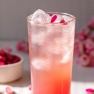 Rose vanilla iced latte with pink-tinted ice and fresh petals